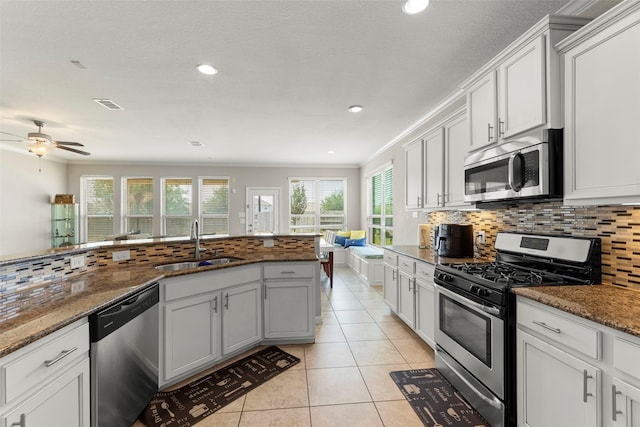20511 Noble Ranch Ct, Richmond, TX 77407 - kitchen with appliances with stainless steel finishes, a sink, light tile patterned flooring, decorative backsplash, and dark stone countertops