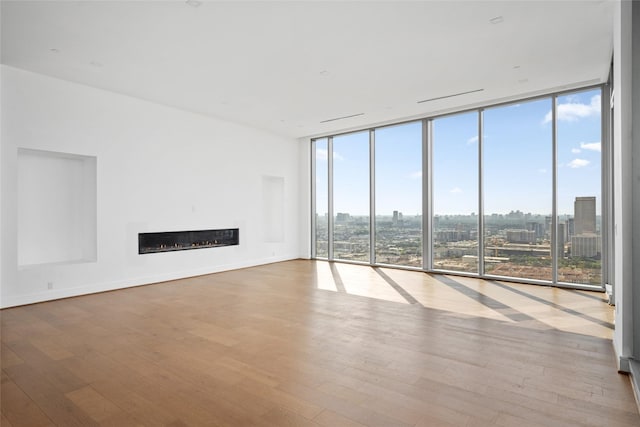 1711 Allen Pkwy Unit 3401, Houston, TX 77019 - unfurnished living room with expansive windows, hardwood / wood-style floors, a glass covered fireplace, a city view, and baseboards
