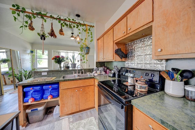 213 N Austin St, Brenham, TX 77833 - kitchen featuring black electric range, a sink, a peninsula, dark countertops, and light wood-style floors