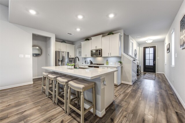 2432 Solaris Bend Dr, Katy, TX 77493 - kitchen with appliances with stainless steel finishes, a sink, dark wood-style flooring, an island with sink, and baseboards