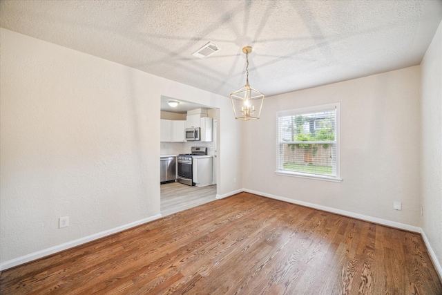 4502 Hain St, Houston, TX 77009 - unfurnished dining area featuring a chandelier, light wood-style floors, baseboards, and a textured ceiling