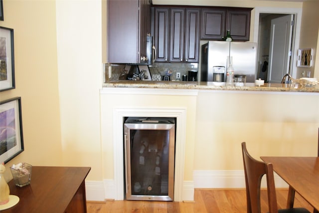 2207 Post Office St, Galveston, TX 77550 - kitchen featuring stainless steel fridge, wine cooler, baseboards, light stone countertops, and light wood finished floors