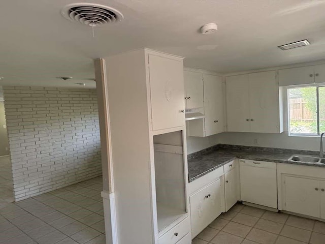426 Pennington Dr, Corpus Christi, TX 78412 - kitchen with white dishwasher, a sink, brick wall, light tile patterned floors, and white cabinetry