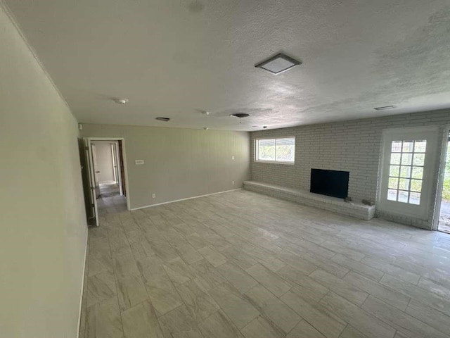 426 Pennington Dr, Corpus Christi, TX 78412 - unfurnished living room with a brick fireplace, a textured ceiling, and baseboards