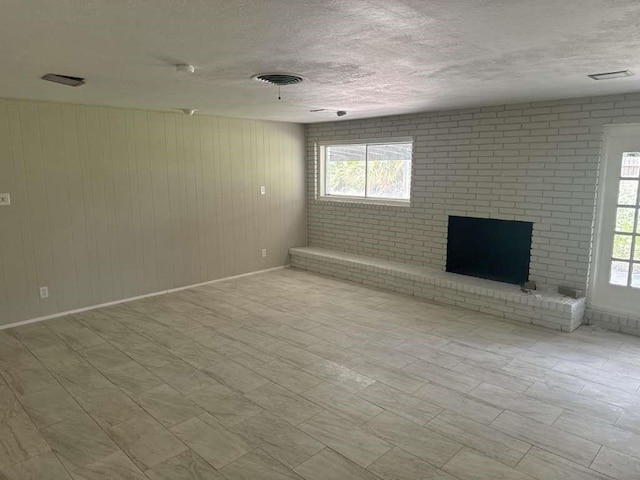 426 Pennington Dr, Corpus Christi, TX 78412 - unfurnished living room featuring baseboards, a brick fireplace, a textured ceiling, and wooden walls