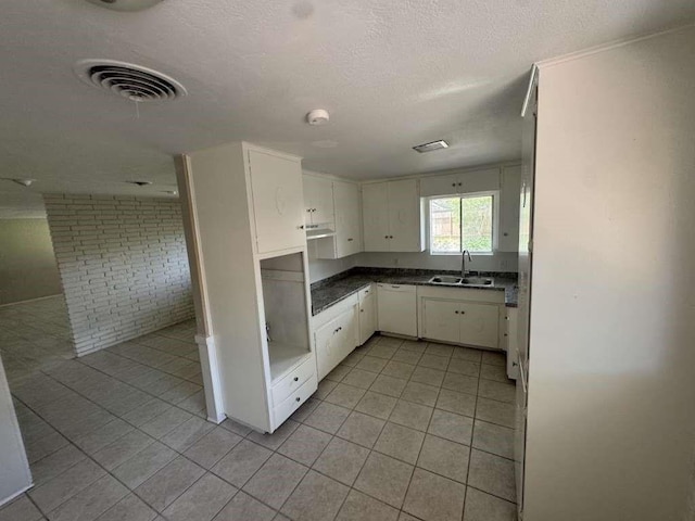 426 Pennington Dr, Corpus Christi, TX 78412 - kitchen with a sink, dishwasher, light tile patterned floors, white cabinetry, and dark countertops