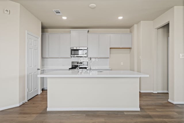 27506 Beachside Arbor Dr, Katy, TX 77493 - kitchen featuring stainless steel appliances, a kitchen island with sink, light countertops, dark wood-type flooring, and recessed lighting