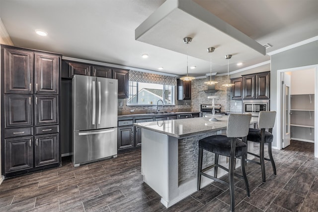 305-335 Omalley Rd, Brenham, TX 77833 - kitchen with appliances with stainless steel finishes, backsplash, a breakfast bar area, ornamental molding, and dark stone counters