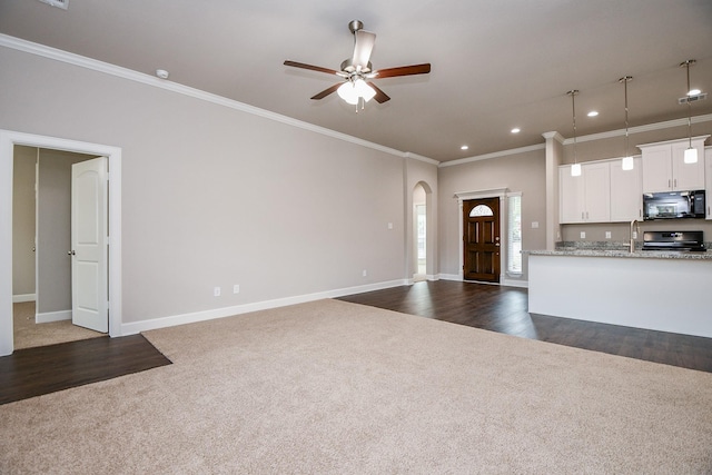 6710 Utah St, Houston, TX 77091 - unfurnished living room featuring dark colored carpet, crown molding, arched walkways, a ceiling fan, and recessed lighting