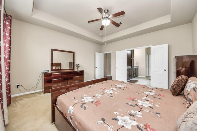 13906 Mowbray Ct, Richmond, TX 77407 - bedroom featuring a raised ceiling, light colored carpet, baseboards, and ensuite bath