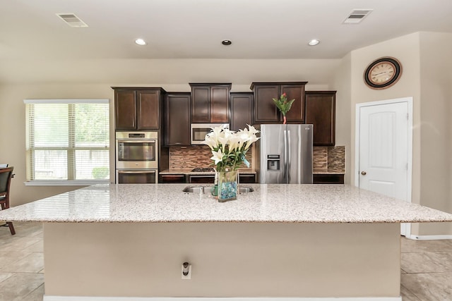 13906 Mowbray Ct, Richmond, TX 77407 - kitchen featuring stainless steel appliances, a kitchen island with sink, light tile patterned floors, tasteful backsplash, and recessed lighting
