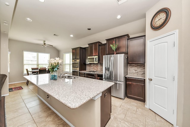 13906 Mowbray Ct, Richmond, TX 77407 - kitchen featuring stainless steel appliances, a sink, ceiling fan, backsplash, and a kitchen island with sink