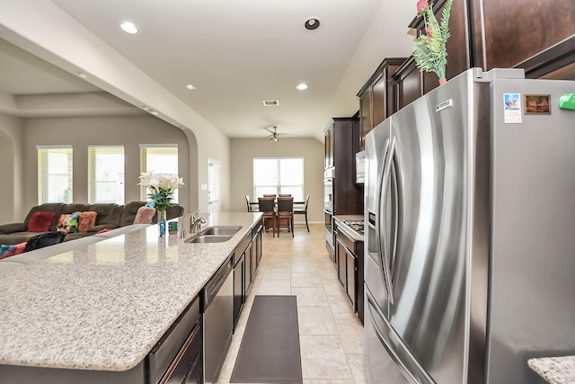 13906 Mowbray Ct, Richmond, TX 77407 - kitchen featuring appliances with stainless steel finishes, a sink, a spacious island, dark brown cabinetry, and open floor plan