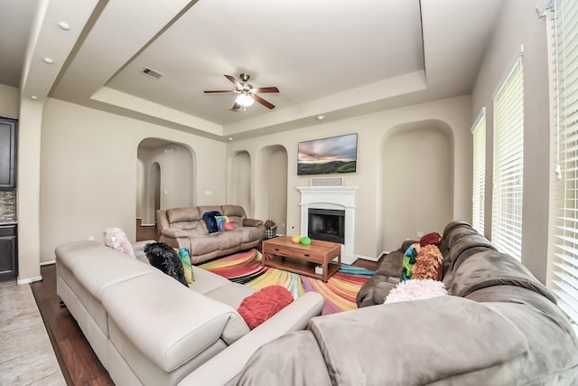 13906 Mowbray Ct, Richmond, TX 77407 - living area with a raised ceiling, a fireplace, arched walkways, ceiling fan, and wood finished floors