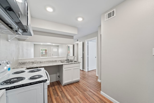 1405 Shadowdale Dr Unit 73, Houston, TX 77043 - kitchen with electric stove, a sink, light wood finished floors, white cabinets, and a peninsula