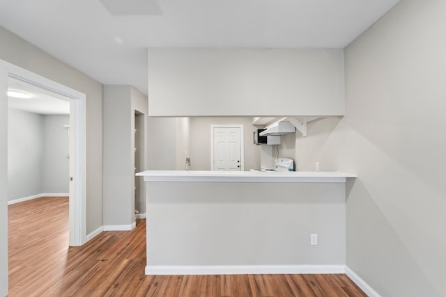 1405 Shadowdale Dr Unit 73, Houston, TX 77043 - kitchen with under cabinet range hood, wood finished floors, a peninsula, and baseboards