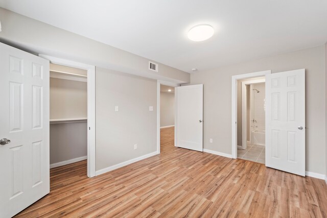 1405 Shadowdale Dr Unit 73, Houston, TX 77043 - unfurnished bedroom featuring light wood-style floors, baseboards, a closet, connected bathroom, and a spacious closet
