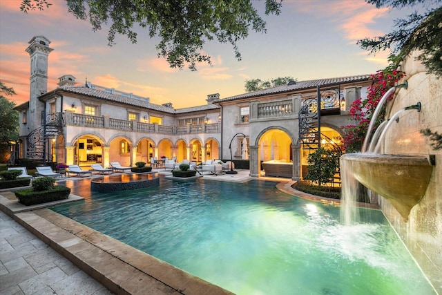2307 River Oaks Blvd, Houston, TX 77019 - back of house featuring a balcony, a patio, an outdoor hangout area, a pool with connected hot tub, and a chimney
