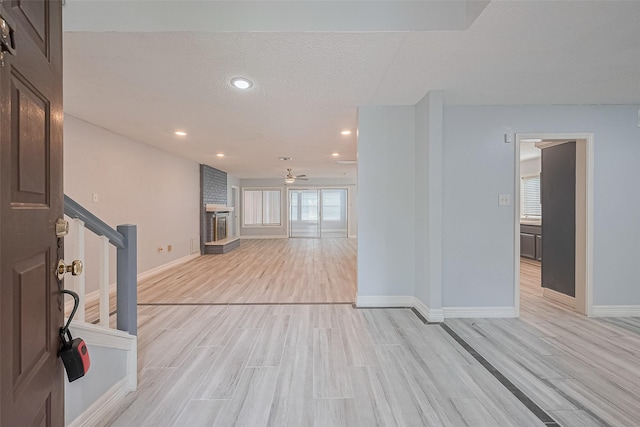 2115 Streamcrest Ln, Sugar Land, TX 77479 - unfurnished living room featuring light wood-style flooring, a ceiling fan, baseboards, a brick fireplace, and recessed lighting
