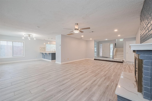 2115 Streamcrest Ln, Sugar Land, TX 77479 - unfurnished living room with light wood-style floors, a textured ceiling, a ceiling fan, baseboards, and stairway