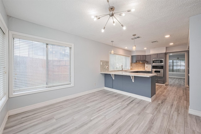 2115 Streamcrest Ln, Sugar Land, TX 77479 - kitchen with stainless steel appliances, a chandelier, a textured ceiling, gray cabinetry, and a breakfast bar