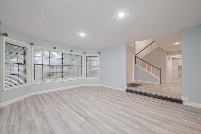 2115 Streamcrest Ln, Sugar Land, TX 77479 - unfurnished living room with a textured ceiling, light wood-style flooring, stairway, baseboards, and recessed lighting