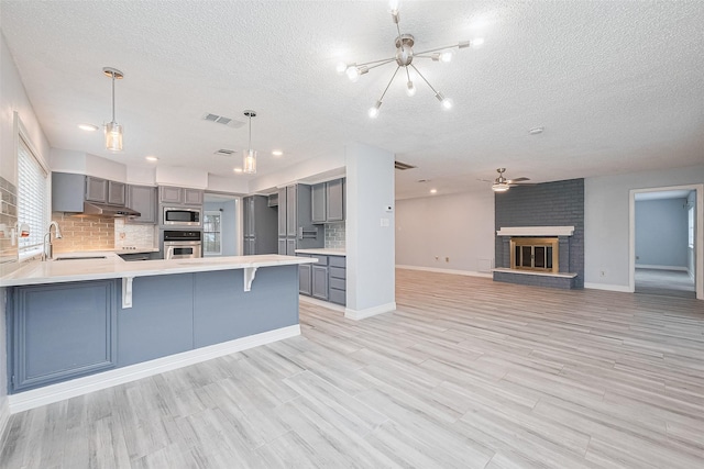 2115 Streamcrest Ln, Sugar Land, TX 77479 - kitchen with gray cabinetry, stainless steel appliances, a textured ceiling, backsplash, and a peninsula