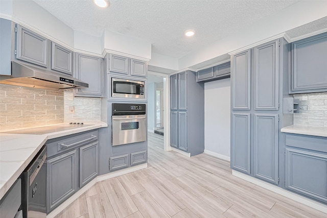 2115 Streamcrest Ln, Sugar Land, TX 77479 - kitchen with appliances with stainless steel finishes, under cabinet range hood, a textured ceiling, light countertops, and decorative backsplash