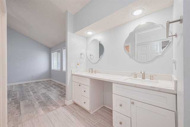 2115 Streamcrest Ln, Sugar Land, TX 77479 - full bathroom featuring a textured ceiling, double vanity, vaulted ceiling, wood finished floors, and baseboards