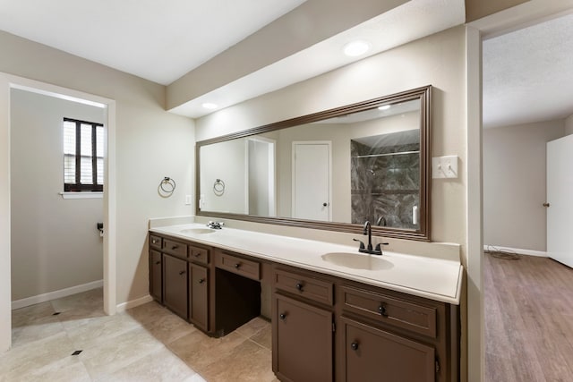 4807 Wind Chimes Dr, Houston, TX 77066 - bathroom with double vanity, a tile shower, and baseboards