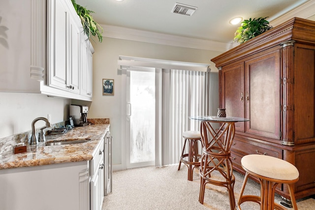 4115 Sand Hill Ct, Galveston, TX 77554 - kitchen featuring a sink, light colored carpet, light stone counters, white cabinetry, and ornamental molding