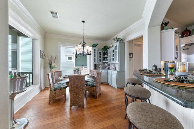 4115 Sand Hill Ct, Galveston, TX 77554 - dining area featuring a chandelier, light wood-type flooring, and crown molding