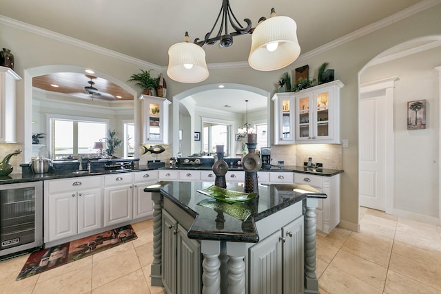 4115 Sand Hill Ct, Galveston, TX 77554 - kitchen featuring beverage cooler, arched walkways, tasteful backsplash, white cabinets, and glass insert cabinets
