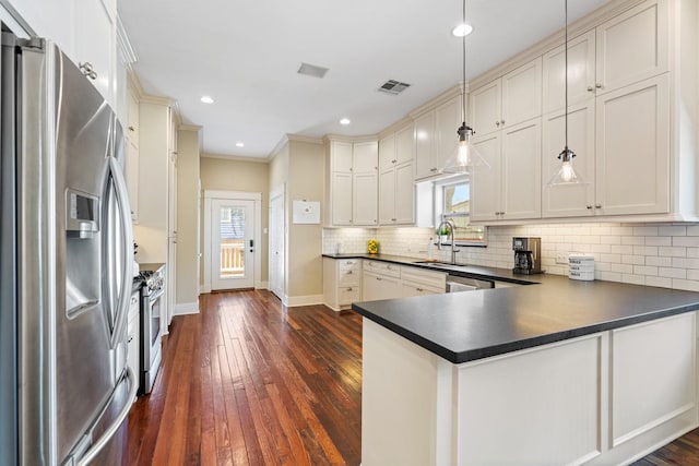 807 Vincent St, Houston, TX 77009 - kitchen with appliances with stainless steel finishes, dark countertops, baseboards, dark wood finished floors, and a peninsula