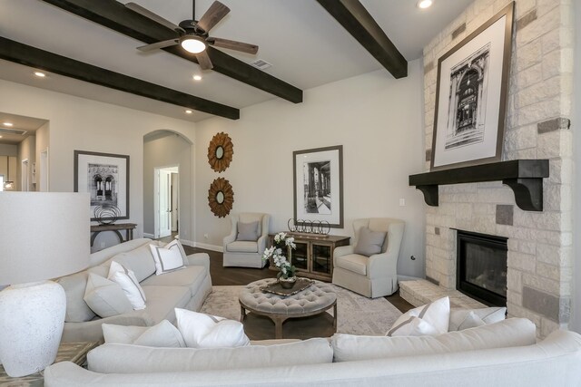 17333 July Moon Ln, Conroe, TX 77302 - living room featuring beamed ceiling, arched walkways, a ceiling fan, a stone fireplace, and wood finished floors