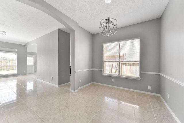1211 Peacham Ct, Fresno, TX 77545 - spare room featuring a textured ceiling, tile patterned floors, a chandelier, arched walkways, and baseboards