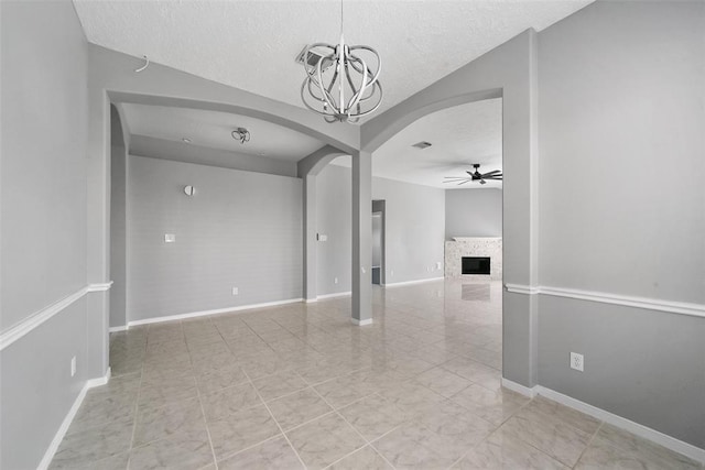 1211 Peacham Ct, Fresno, TX 77545 - empty room with a ceiling fan, a chandelier, a textured ceiling, arched walkways, and a fireplace