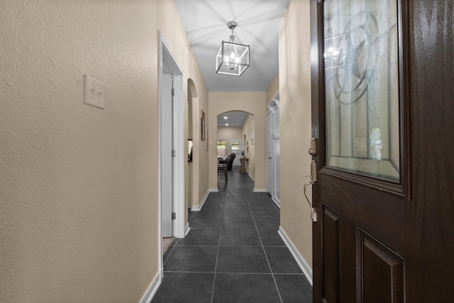 28987 Birch Green Way, Spring, TX 77386 - hall featuring arched walkways, dark tile patterned floors, baseboards, a chandelier, and a textured wall
