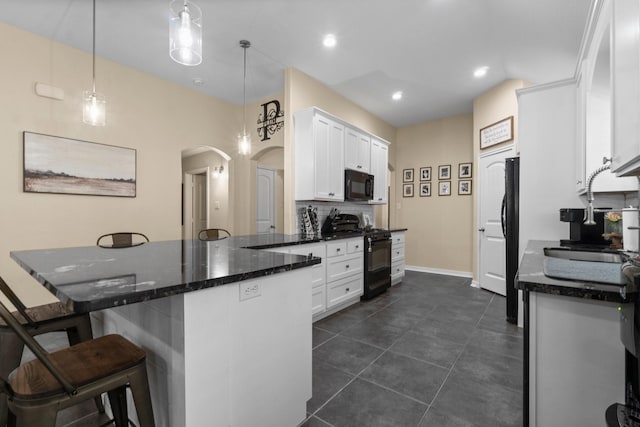 28987 Birch Green Way, Spring, TX 77386 - kitchen with black appliances, a sink, arched walkways, white cabinetry, and a kitchen breakfast bar