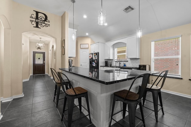 28987 Birch Green Way, Spring, TX 77386 - kitchen with black fridge, arched walkways, a kitchen bar, a sink, and white cabinetry