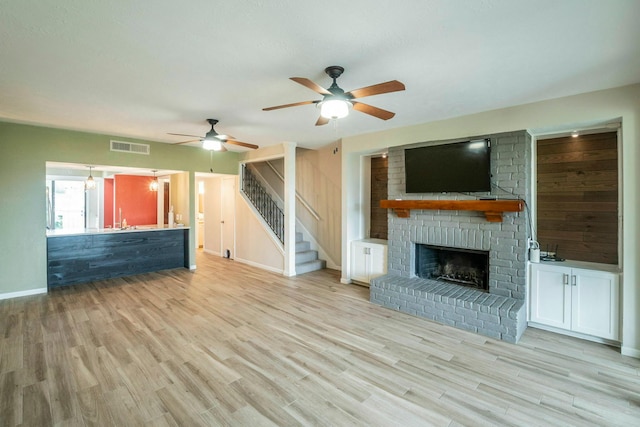 2304 Keel Ct, Willis, TX 77318 - unfurnished living room featuring a ceiling fan, a fireplace, wood finished floors, stairs, and baseboards