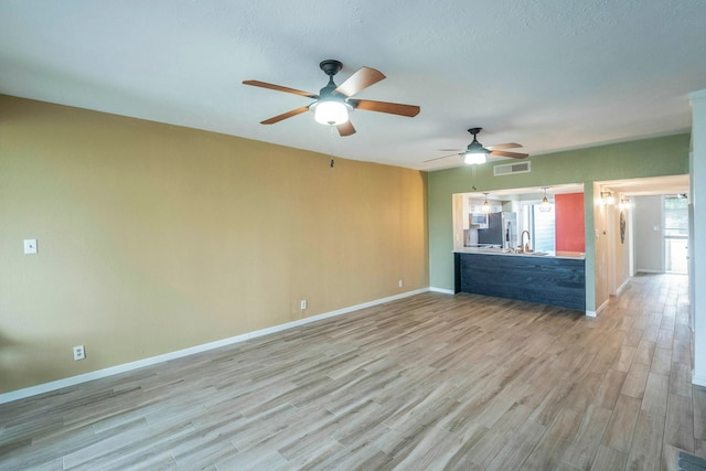 2304 Keel Ct, Willis, TX 77318 - unfurnished living room with light wood finished floors, ceiling fan, a sink, and baseboards
