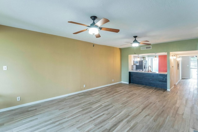 2304 Keel Ct, Willis, TX 77318 - unfurnished living room with light wood-type flooring, ceiling fan, baseboards, and a sink