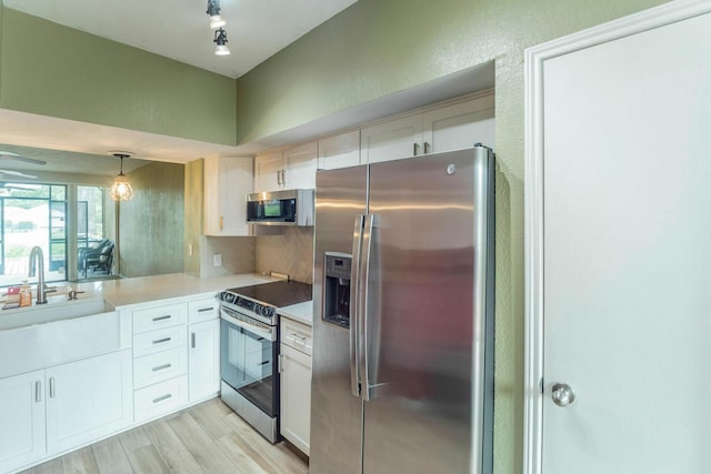 2304 Keel Ct, Willis, TX 77318 - kitchen with appliances with stainless steel finishes, a sink, light countertops, light wood finished floors, and white cabinets