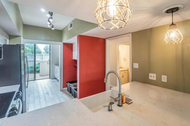 2304 Keel Ct, Willis, TX 77318 - kitchen with a sink, range, a chandelier, decorative light fixtures, and light wood-style flooring