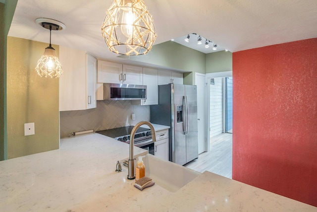 2304 Keel Ct, Willis, TX 77318 - kitchen with stainless steel appliances, backsplash, a chandelier, light stone counters, and white cabinets