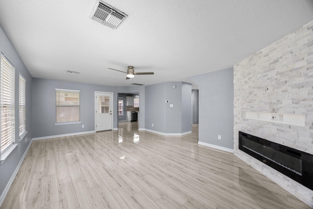 612 Hartman Dr, Baytown, TX 77521 - unfurnished living room featuring a fireplace, a ceiling fan, a textured ceiling, baseboards, and light wood finished floors
