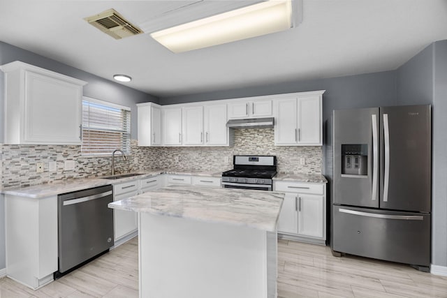 612 Hartman Dr, Baytown, TX 77521 - kitchen with stainless steel appliances, a sink, under cabinet range hood, white cabinetry, and tasteful backsplash