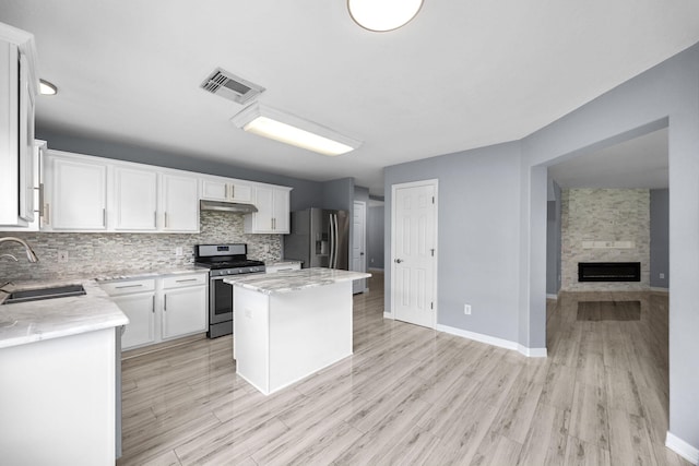 612 Hartman Dr, Baytown, TX 77521 - kitchen with appliances with stainless steel finishes, a sink, under cabinet range hood, decorative backsplash, and a kitchen island