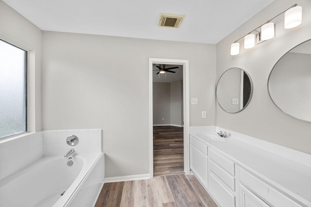 612 Hartman Dr, Baytown, TX 77521 - bathroom featuring wood finished floors, a bath, vanity, baseboards, and ceiling fan